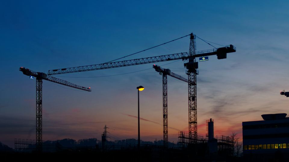 Grues de chantier en silhouette dans le ciel du soir
